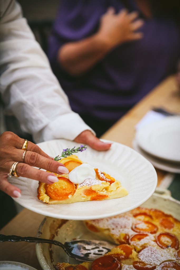 holding plate with slice of apricot clafoutis placing piece of lavender to style